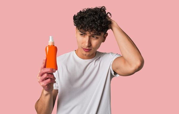Man scratching his head with a bottle of vinegar in his hand showing how to use it
