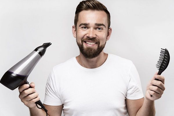 Man smiling holding brush hair dryer