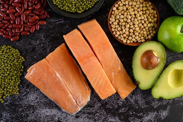 Legumes, fruit, and salmon placed on a black cement floor