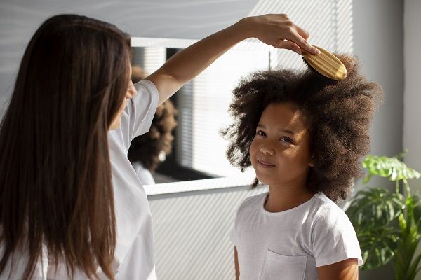Mom helping her child styling afro hair