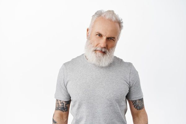 Man posing with white rooted hair and tattoos on his arms