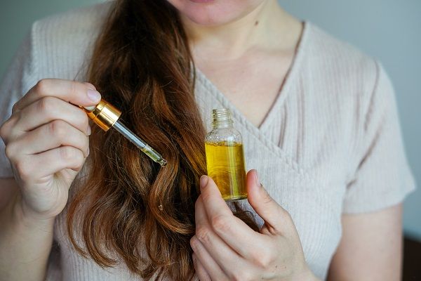 Woman applying argan oil to her hair